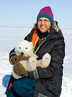 Nick Lunn, polar bear researcher for Environment Canada, uses the cub of a drugged female for a photo op